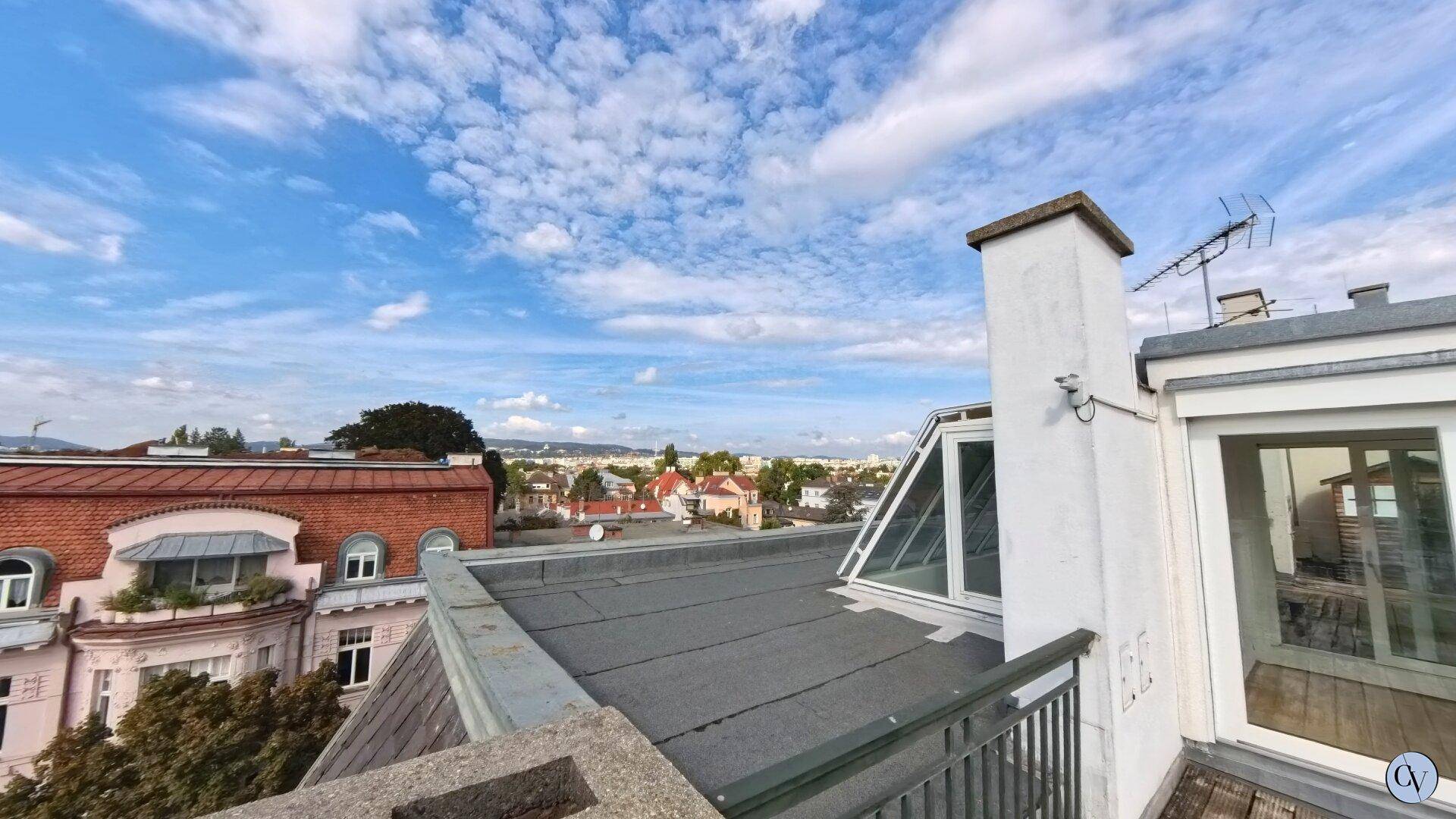 Weitläufiger Blick über die Dächer der Stadt mit blauem Himmel und Wolken.