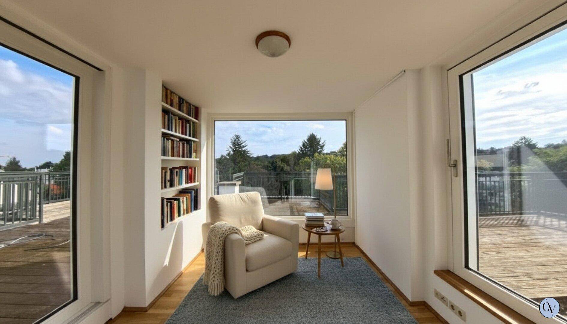 Gemütlicher Lesebereich mit Sessel, Bücherregal und weitem Blick ins Grüne von der Terrasse.