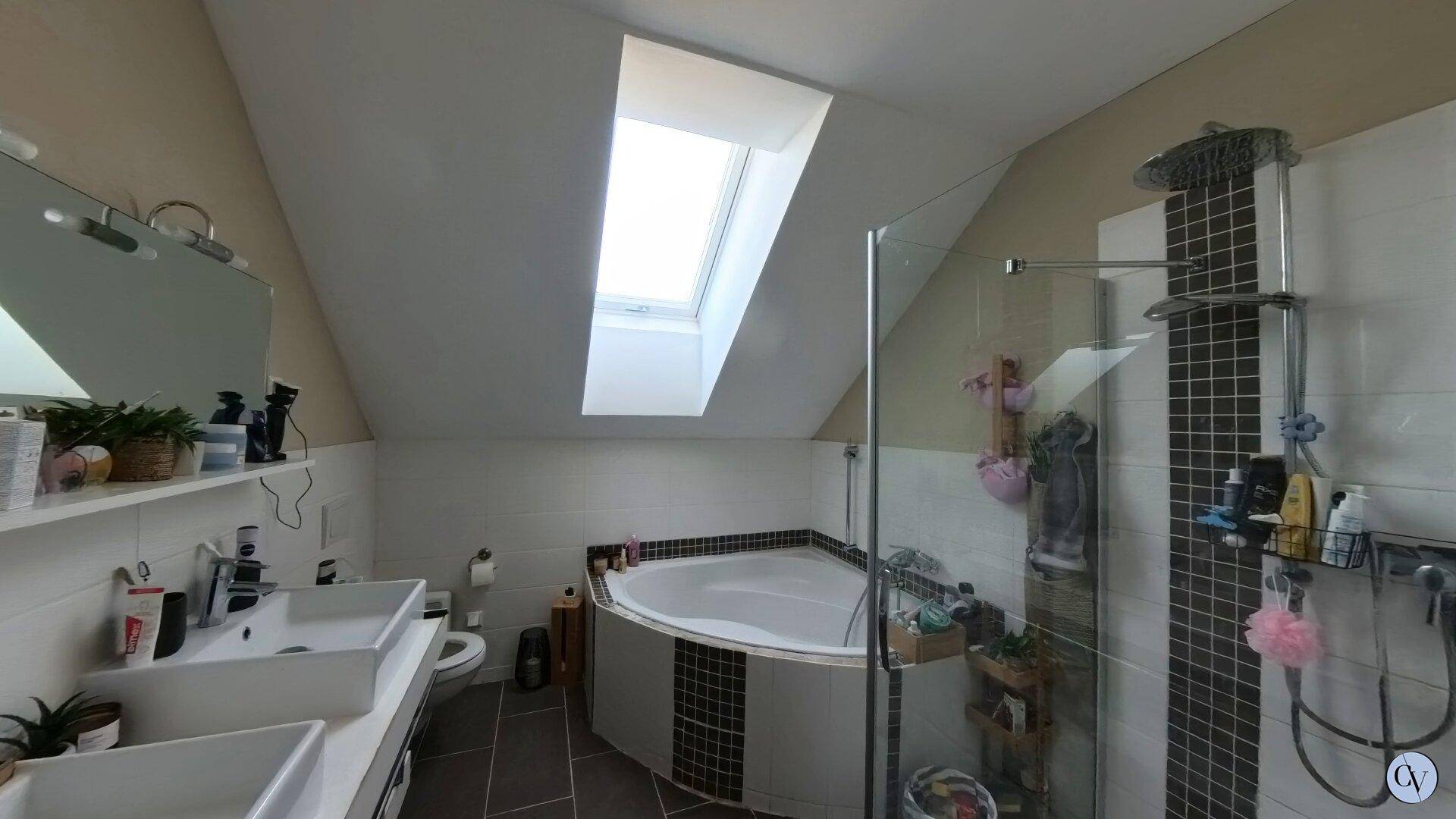 Modernes Badezimmer im Dachgeschoss mit Eckbadewanne, Dusche und Oberlicht für Tageslicht.