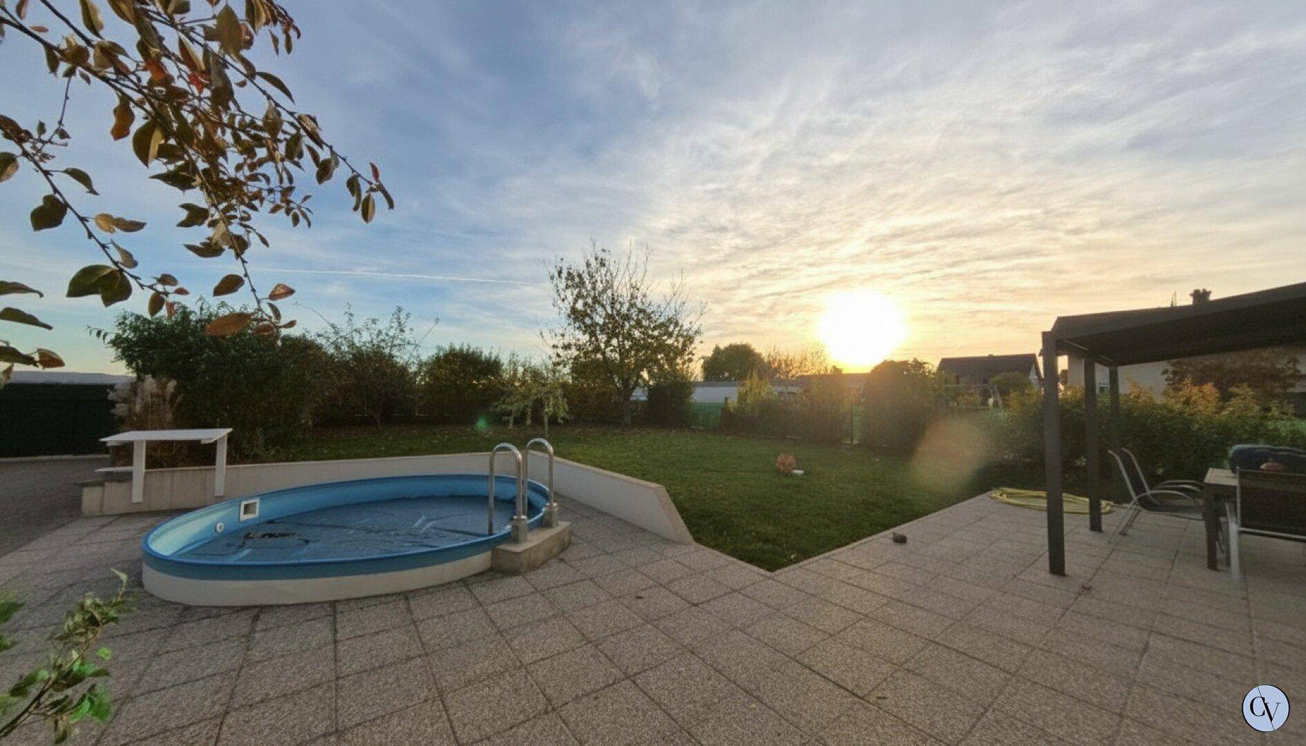 Sonnenuntergang im Garten mit kleinem Pool und angrenzender Terrasse, umgeben von Grünflächen.