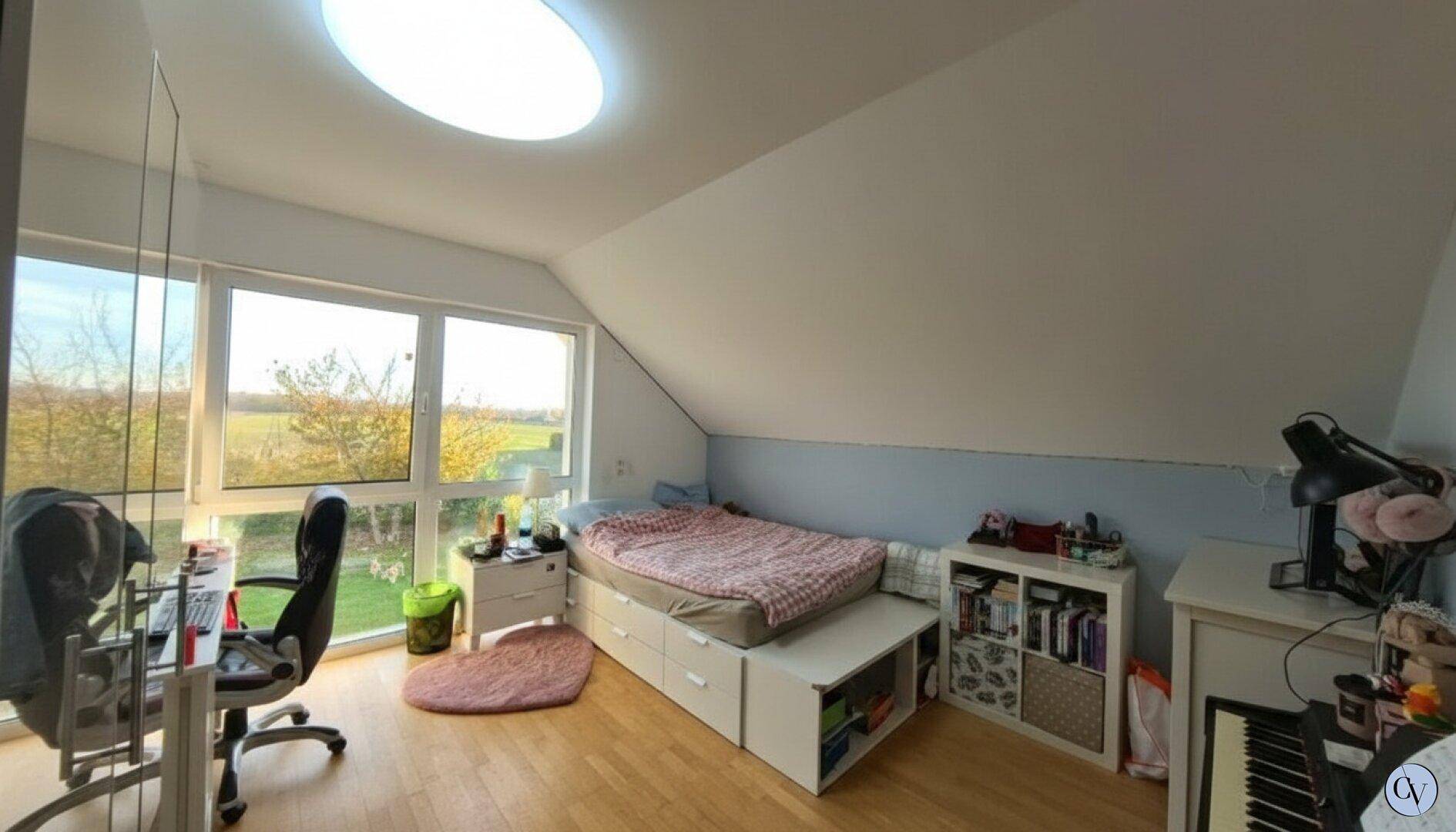 Gemütliches Schlafzimmer im Dachgeschoss mit Schräge, großem Fenster und Oberlicht.