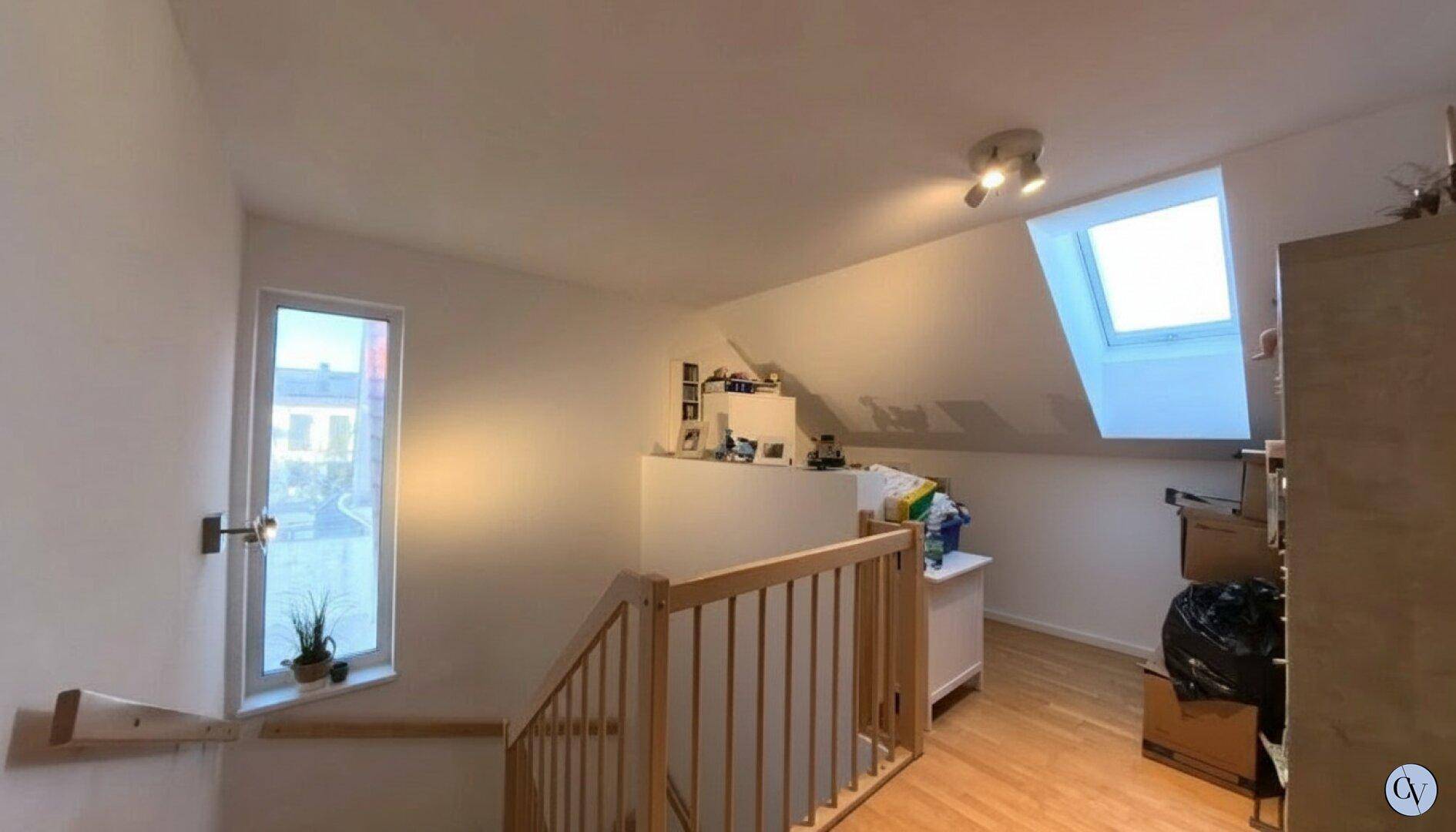 Heller Flur im Obergeschoss mit Holztreppe und Dachfenster, das Tageslicht spendet.