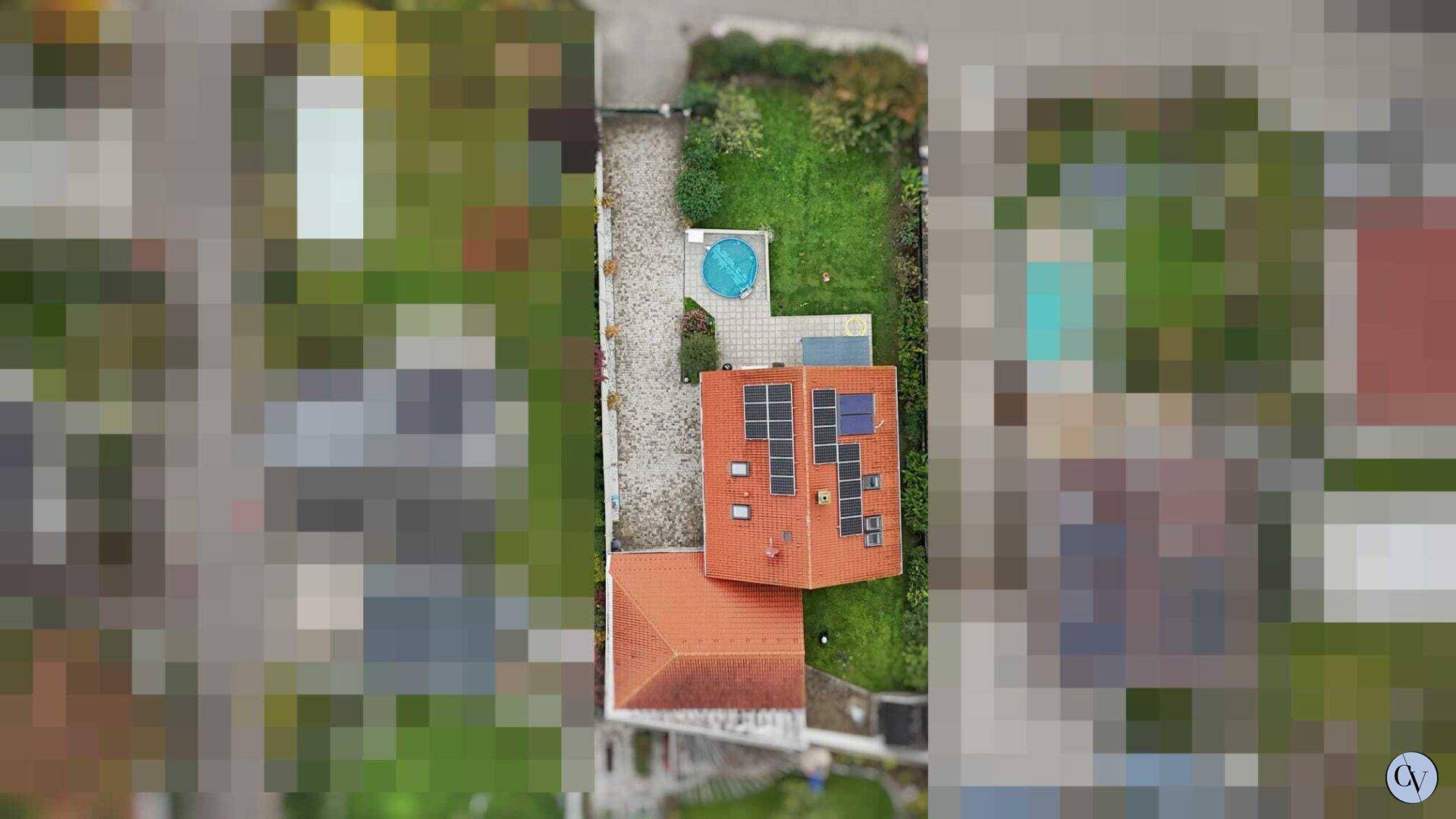 Draufsicht auf das Wohnhaus mit rotem Ziegeldach, Solarpaneelen und kleinem Pool im Garten.