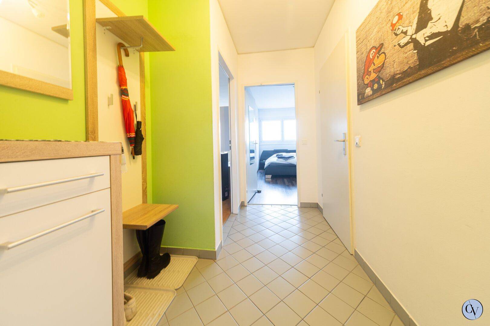 Heller Flur mit Fliesenboden, Garderobe und Zugang zu den weiteren Räumen.