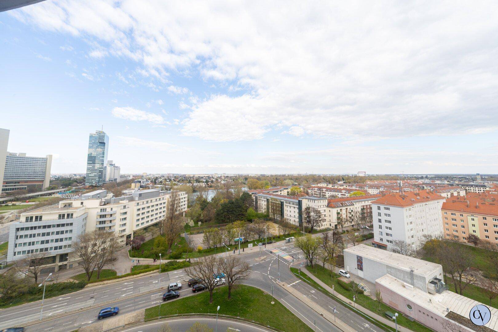 Weitläufiger Blick über die Stadt mit Gebäuden, Straßen und Grünflächen.
