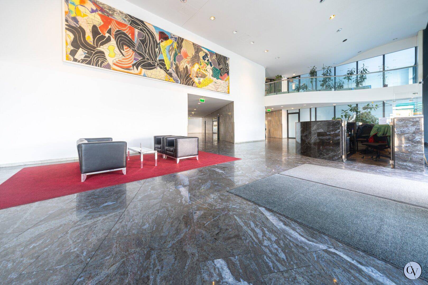 Elegante Lobby mit Marmorboden, Kunstwerk und Sitzgelegenheiten im Eingangsbereich.