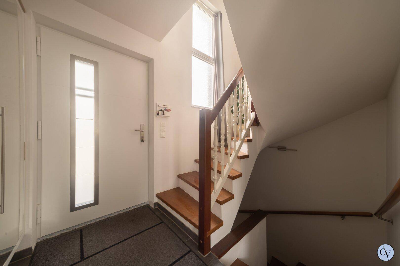Heller Eingangsbereich mit Treppe zum Obergeschoss und natürlichem Lichteinfall.