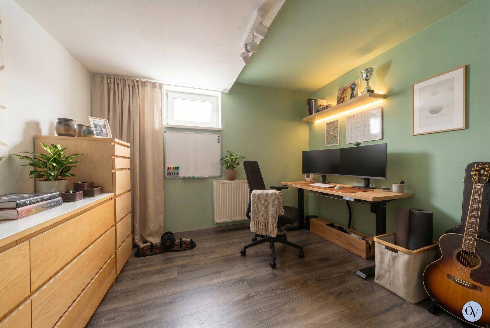 Funktionales Büro mit Schreibtisch, Regalen und grün gestrichenen Wänden.