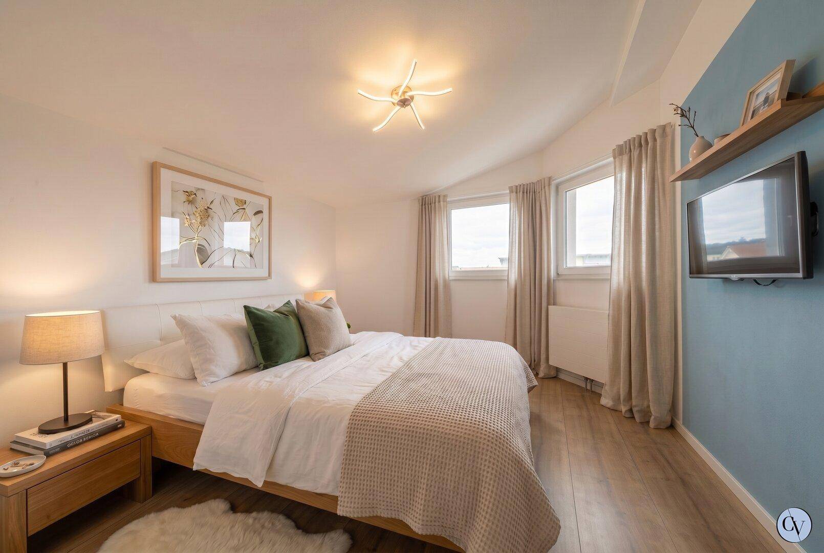 Gemütliches Schlafzimmer mit Holzboden, Doppelbett und blauer Akzentwand.