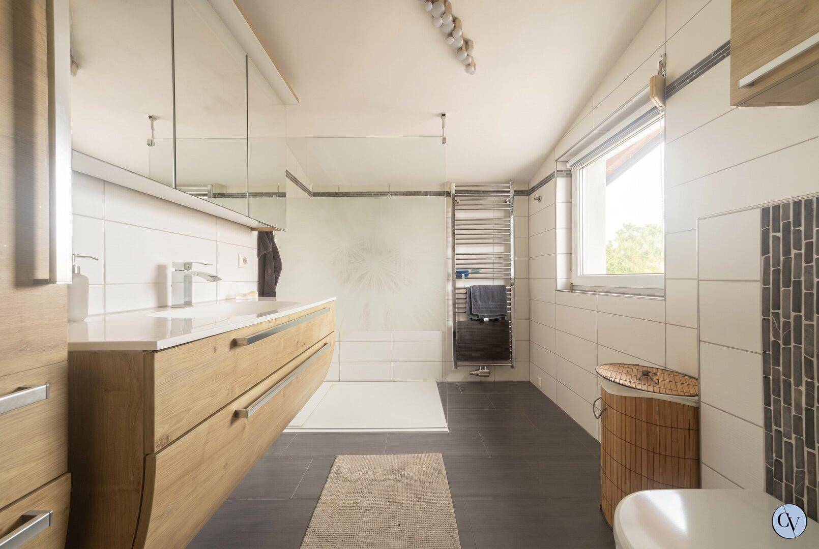 Modernes Badezimmer mit großem Waschtisch, begehbarer Dusche und Fenster.