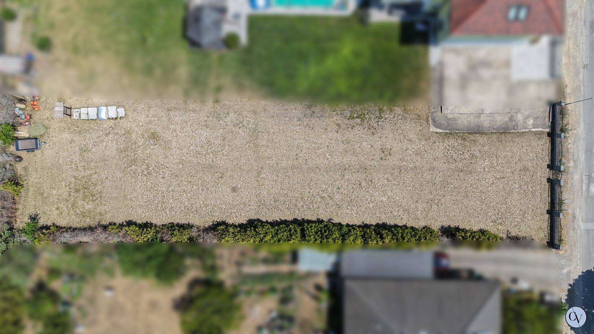 Luftaufnahme eines rechteckigen Grundstücks mit Hecke und angrenzenden Häusern.