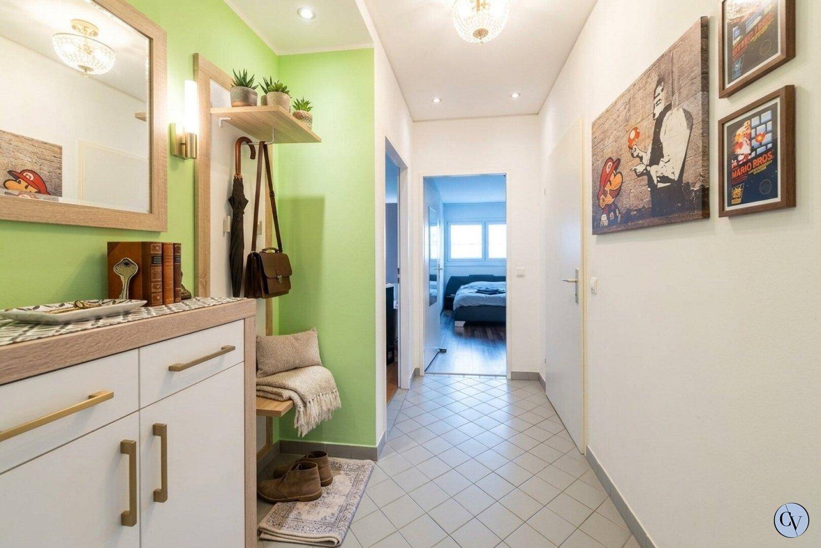 Freundlicher Flur mit hellgrüner Akzentwand, Spiegelschrank und Fliesenboden.