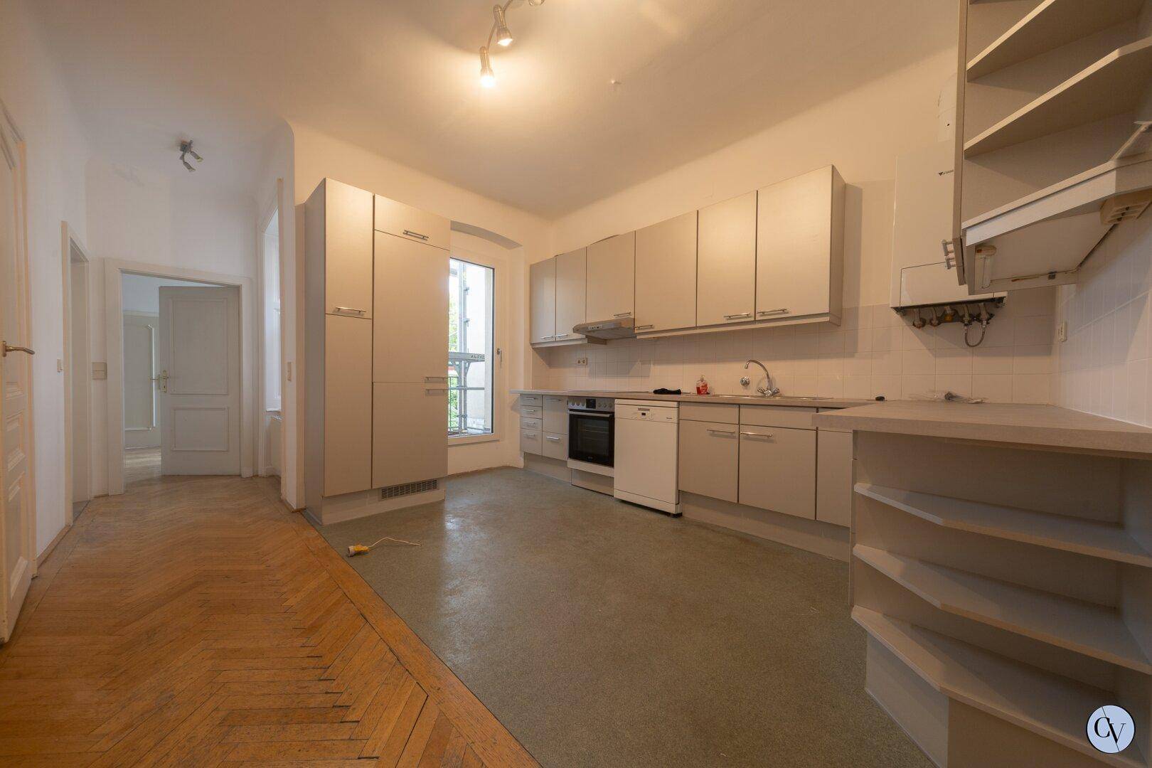 Funktionale Küche mit Einbauschränken, Spülmaschine und Fenster.