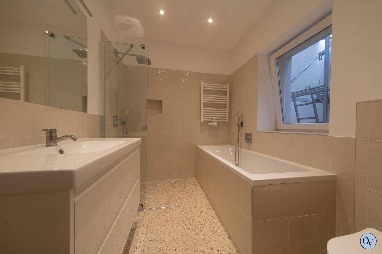 Modernes Badezimmer mit Badewanne, Dusche, Einzelwaschbecken und Fenster.
