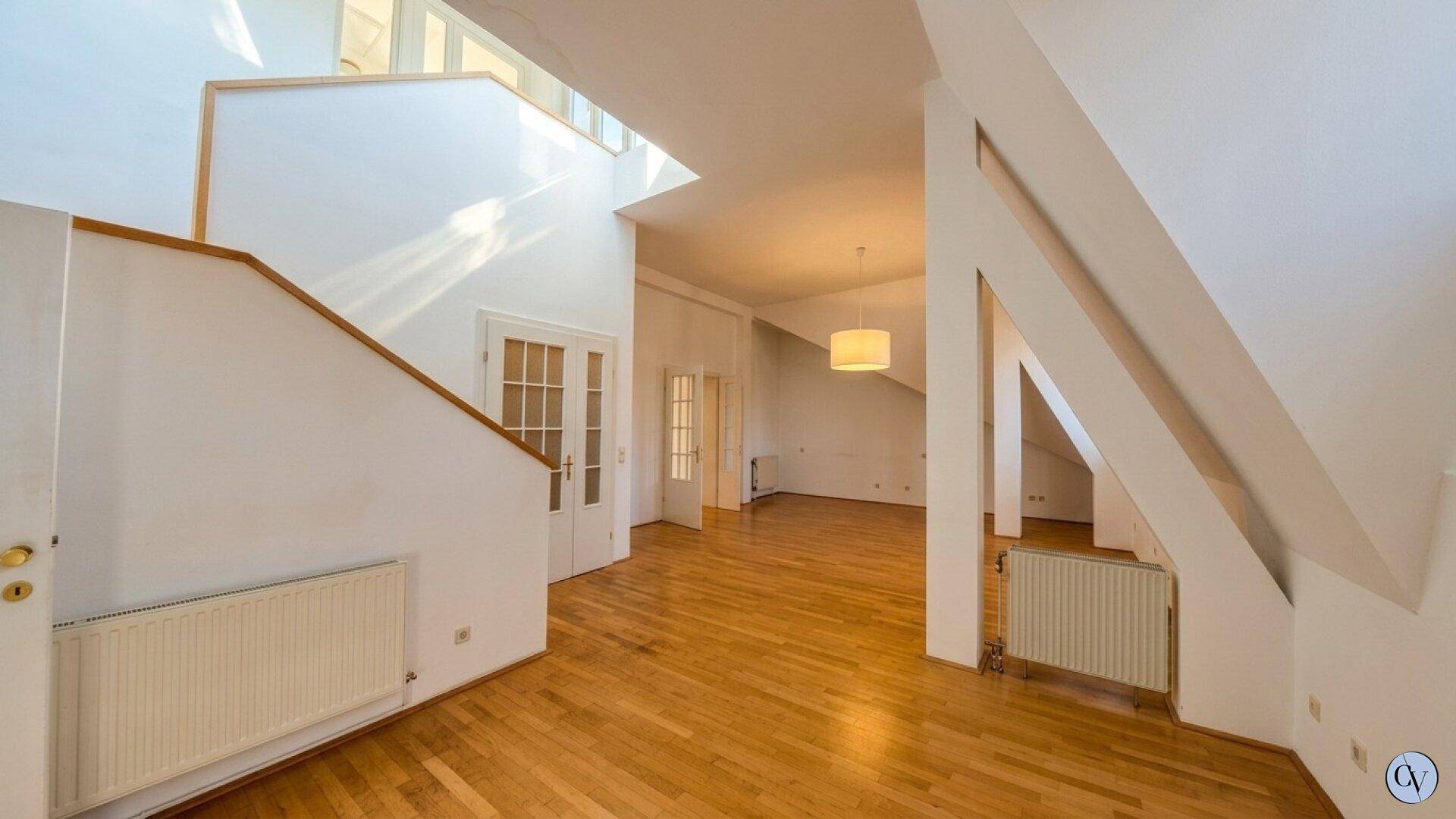 Helles Wohnzimmer mit Holzboden, Dachschrägen und viel Tageslicht.