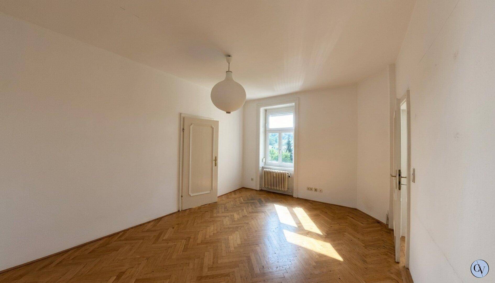 Geräumiges Schlafzimmer mit Parkettboden und einem Fenster.