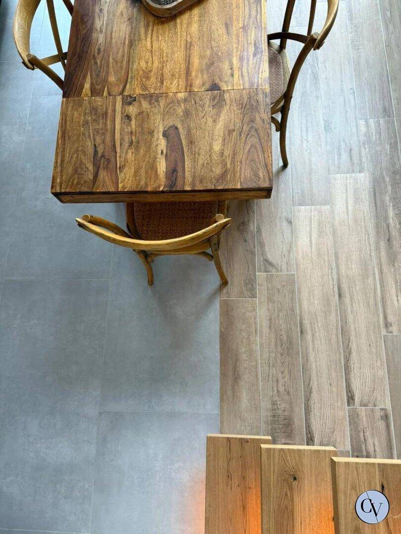 Essbereich mit Holztisch und Stühlen, kombiniert mit Fliesen- und Holzoptik-Bodenbelag.