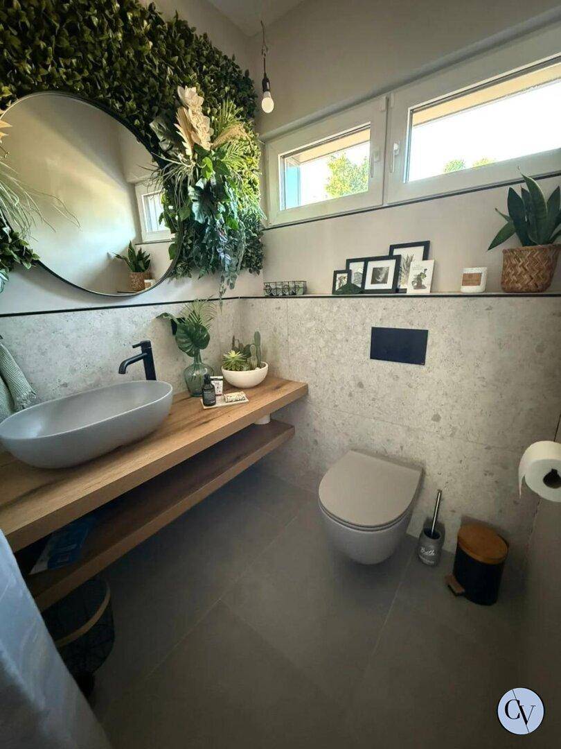 Modernes Gäste-WC mit Wand-WC, Aufsatzwaschbecken und dekorativer Pflanzenwand.
