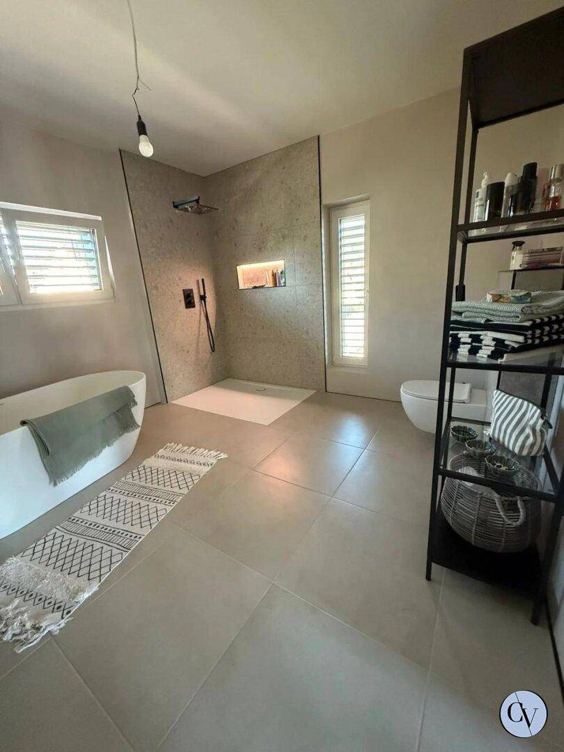 Helles Badezimmer mit freistehender Badewanne, begehbarer Dusche und wandhängendem WC.