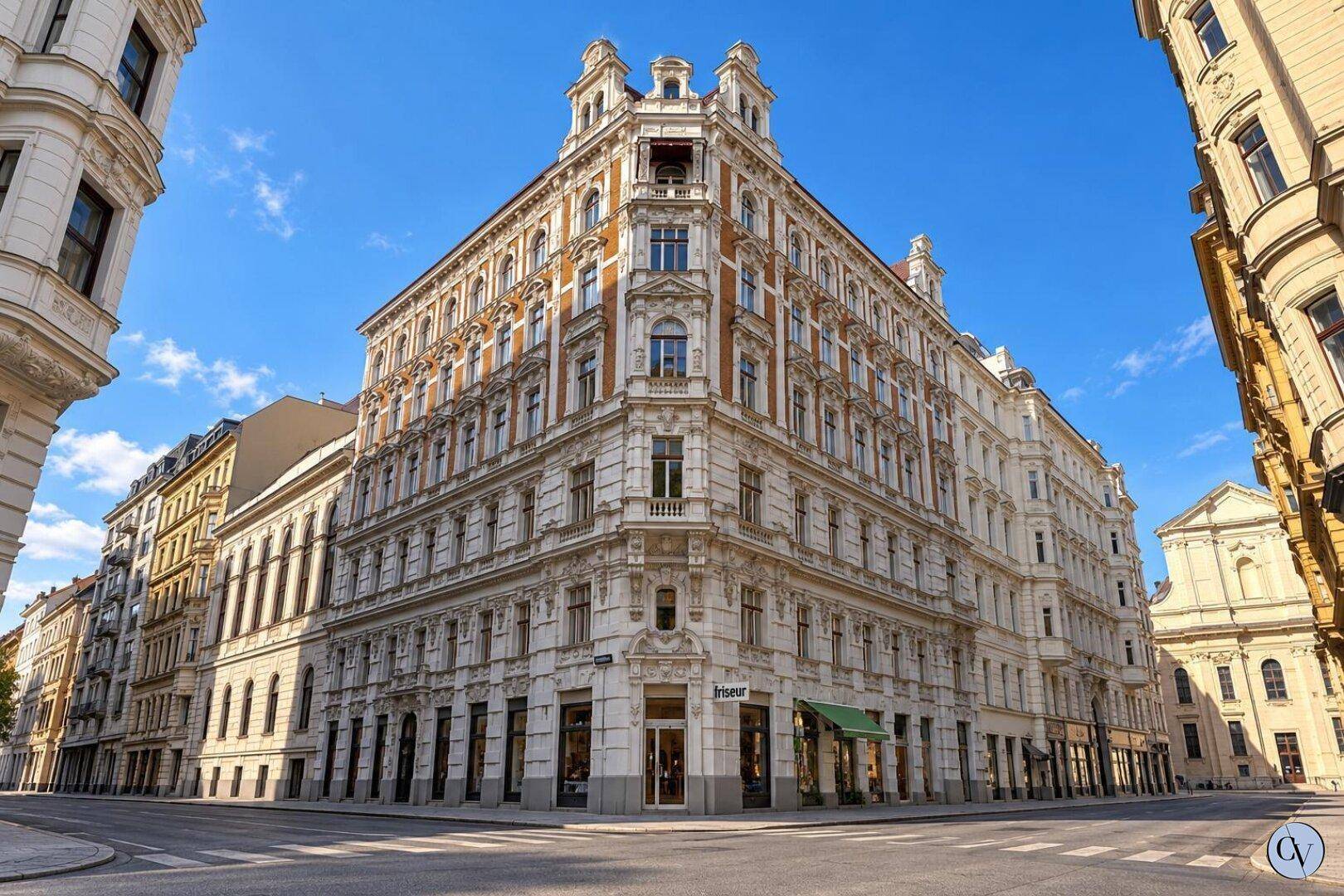 Prächtiges Eckgebäude mit historischer Architektur, vielen Fenstern und Geschäften im Erdgeschoss.