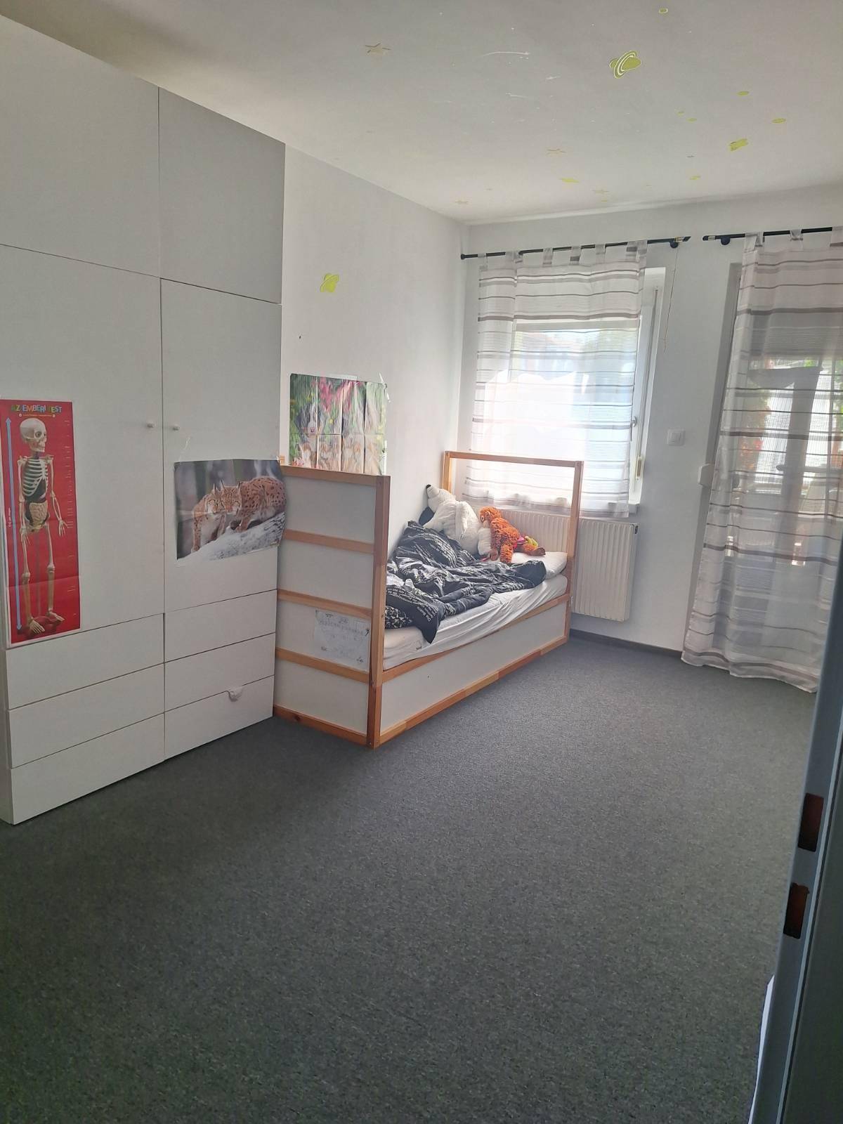 Helles Kinderzimmer mit Teppichboden, weißem Kleiderschrank und einem gemütlichen Einzelbett.