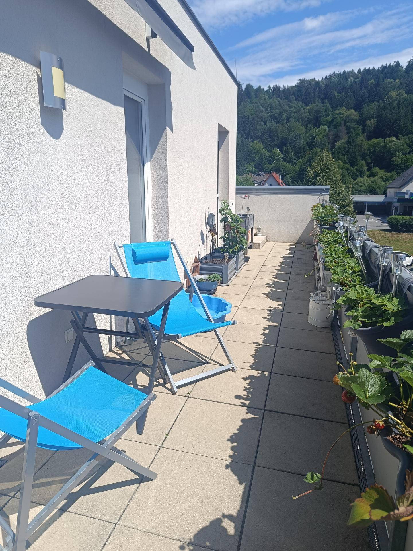 Sonniger Balkon mit Sitzgelegenheiten und Pflanzen, ideal zum Entspannen mit Blick ins Grüne.
