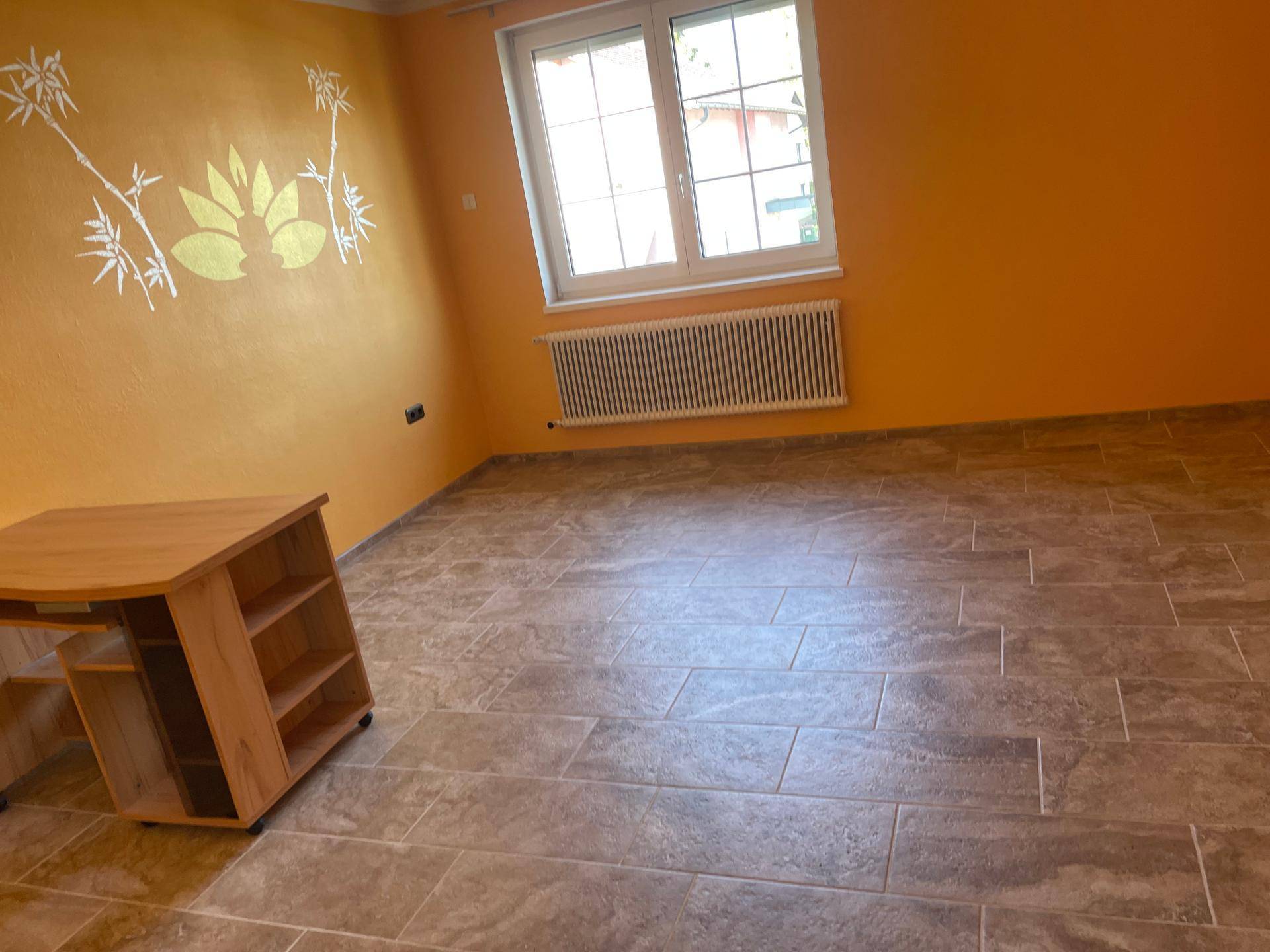 Schlafzimmer mit orangefarbenen Wänden, Fliesenboden und dekorativem Wandmotiv.