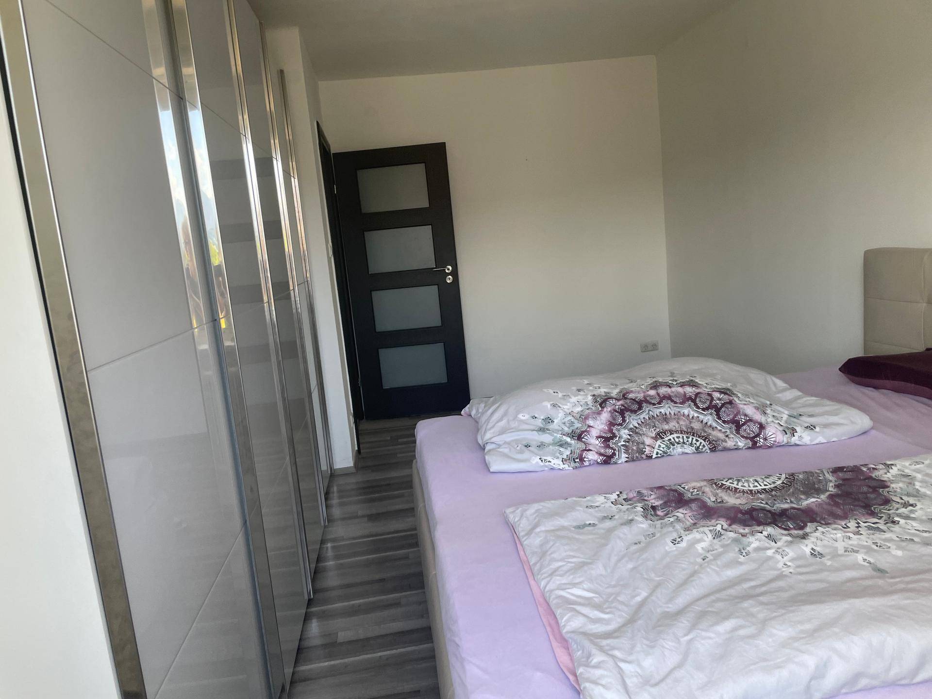 Schlafzimmer mit modernem Bett und eleganten weißen Hochglanzschränken, die viel Stauraum bieten.