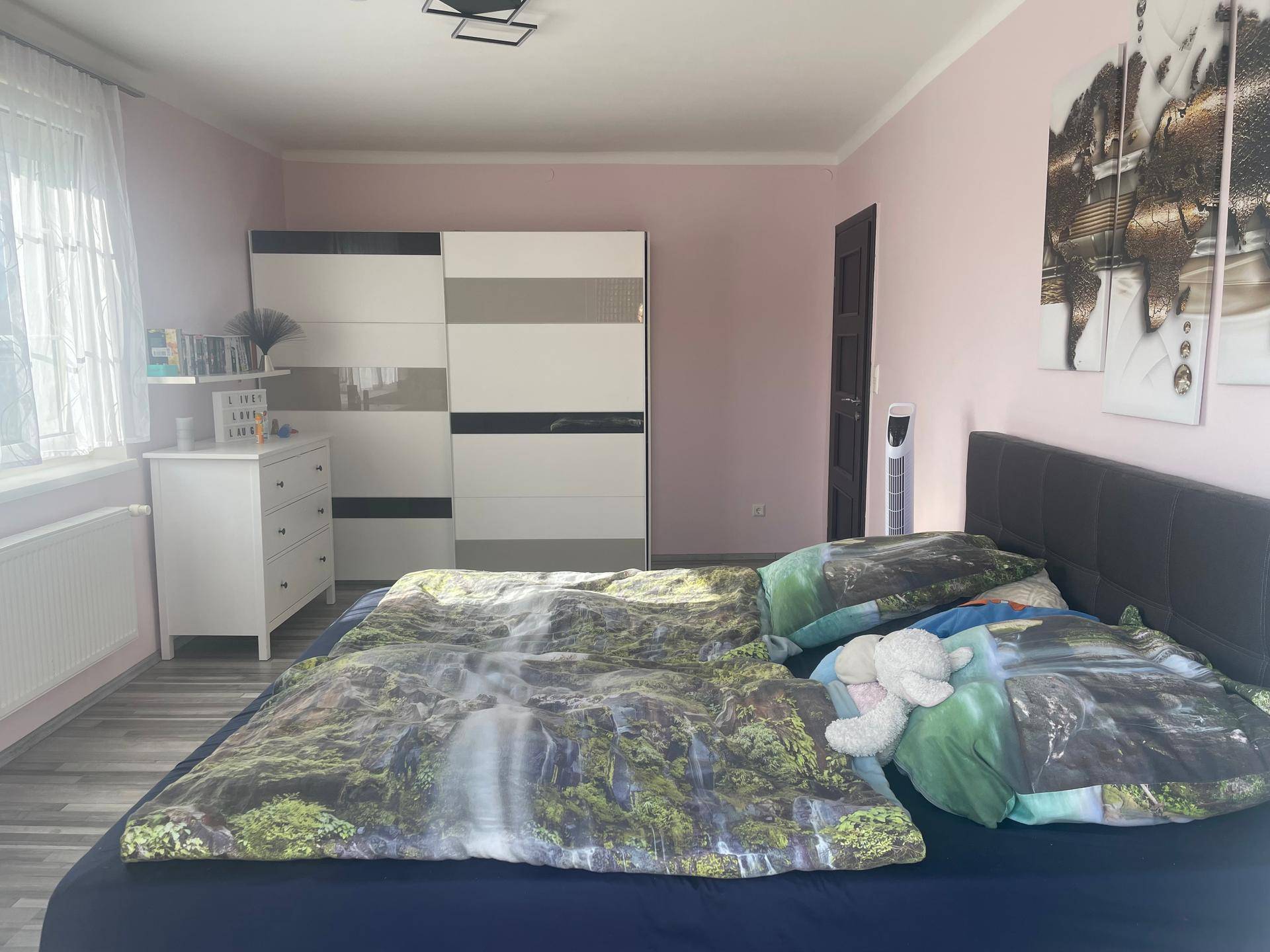Schlafzimmer mit großem Bett, farbenfroher Bettwäsche und einem modernen Kleiderschrank für Komfort.