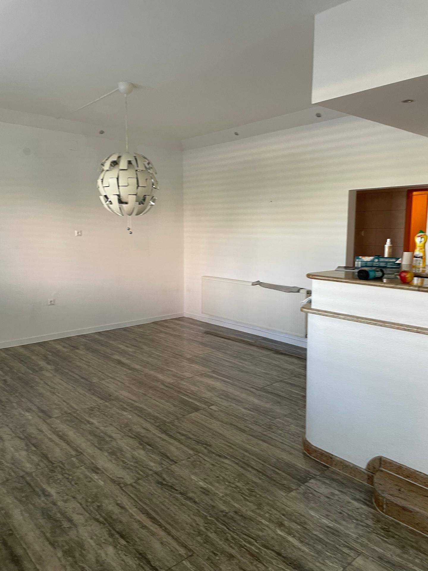 Heller Essbereich mit Laminatboden, moderner Pendelleuchte und Thekenbereich.