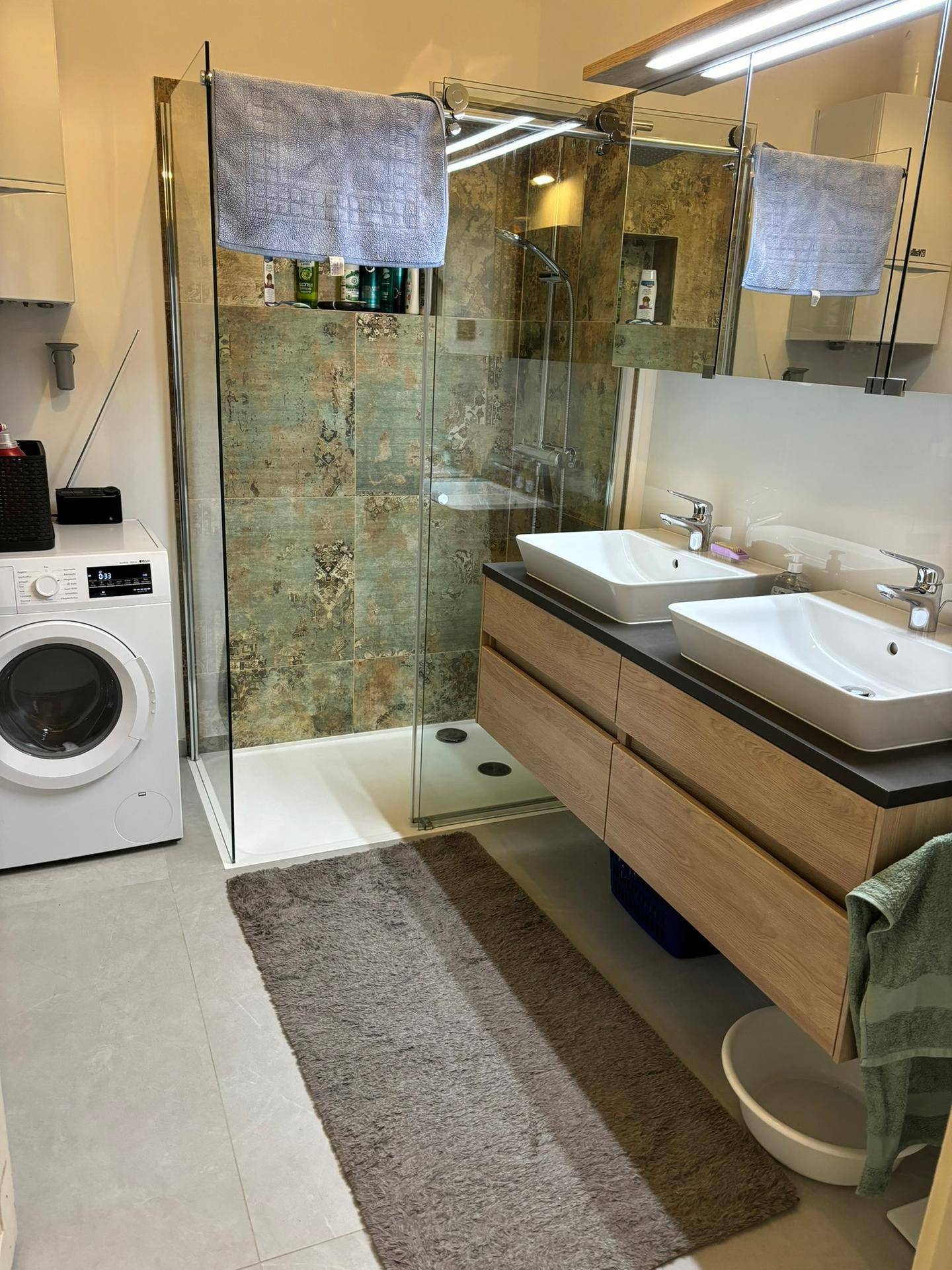 Modernes Badezimmer mit Doppelwaschbecken, großer begehbarer Dusche und Waschmaschine.
