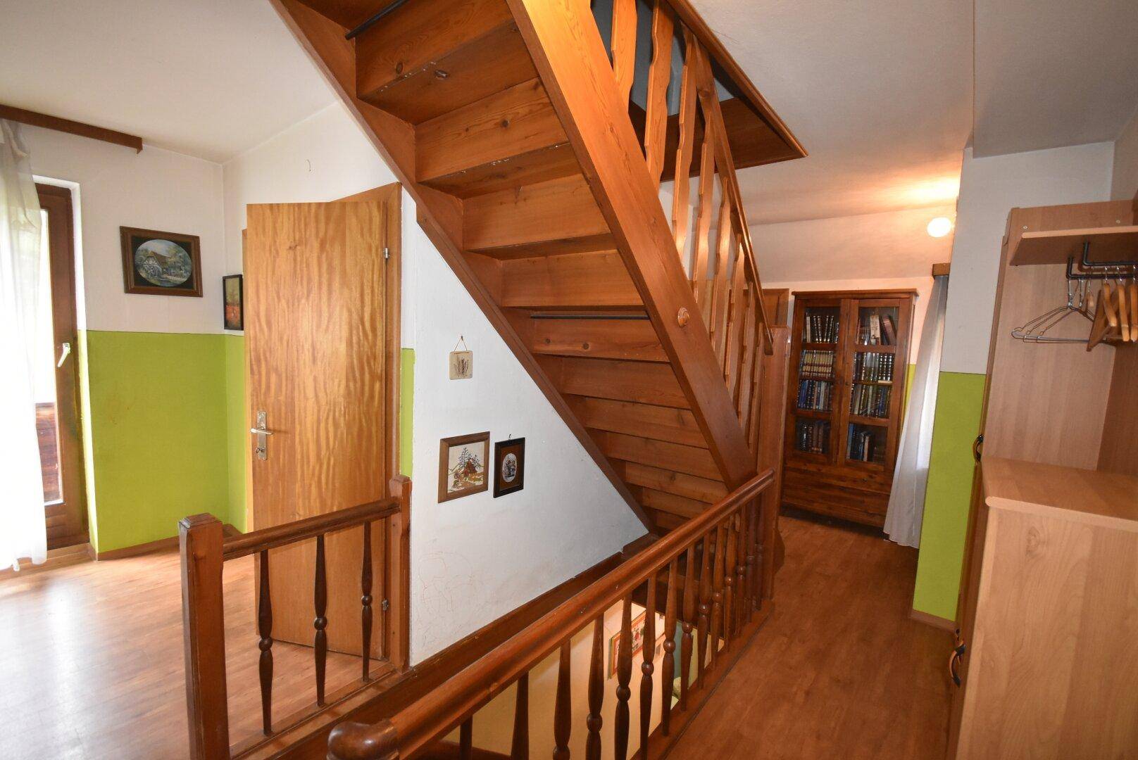 Heller Flur mit Holztreppe, Holzboden und Zugang zu weiteren Räumen.