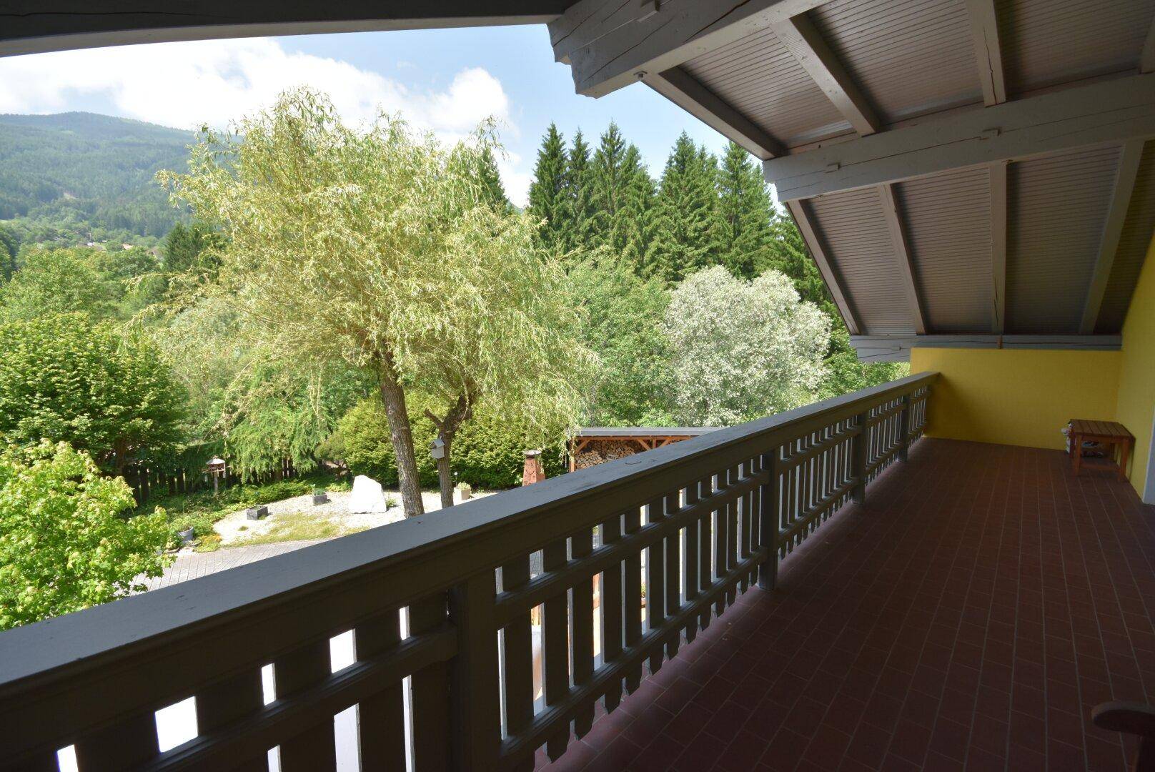 Geräumiger Balkon mit Holzgeländer und weitem Blick auf die umliegende Berglandschaft.