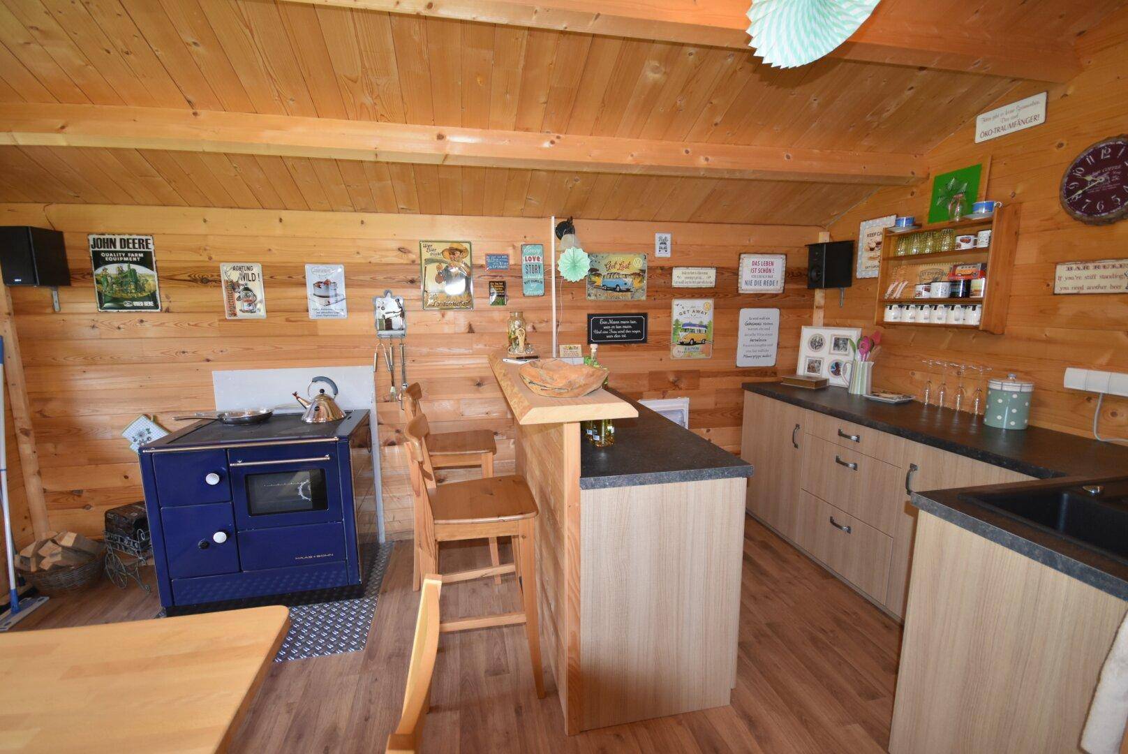 Rustikale Holzküche mit kleiner Bar, blauem Ofen und vielen dekorativen Schildern an den Wänden.