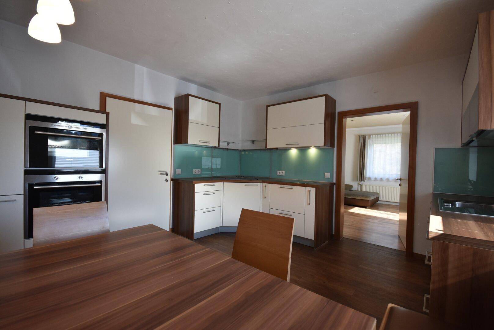 Moderne Einbauküche mit hellen Fronten, Holzdetails und integrierten Geräten.