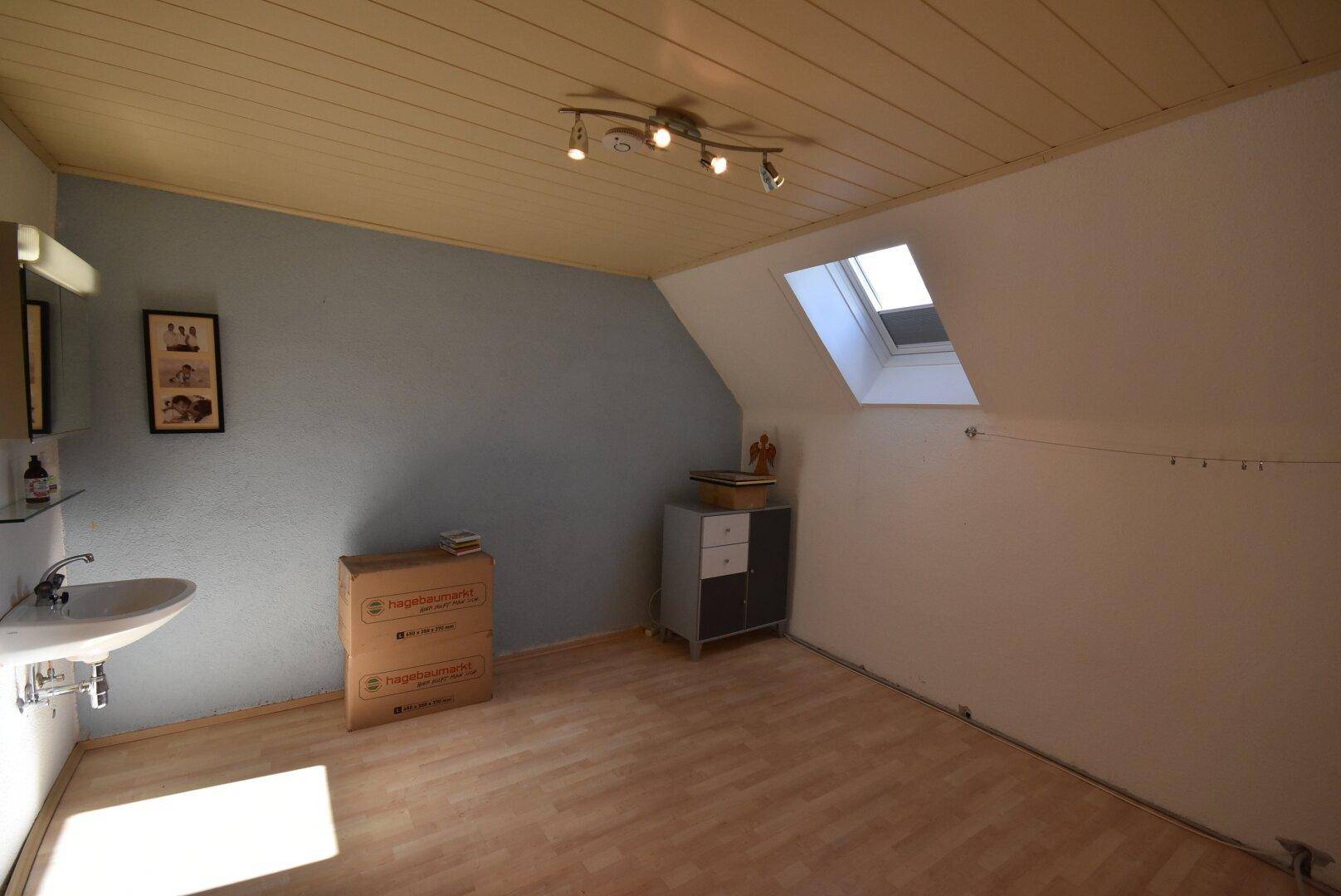 Dachzimmer mit Schräge, Dachfenster und Waschbecken.