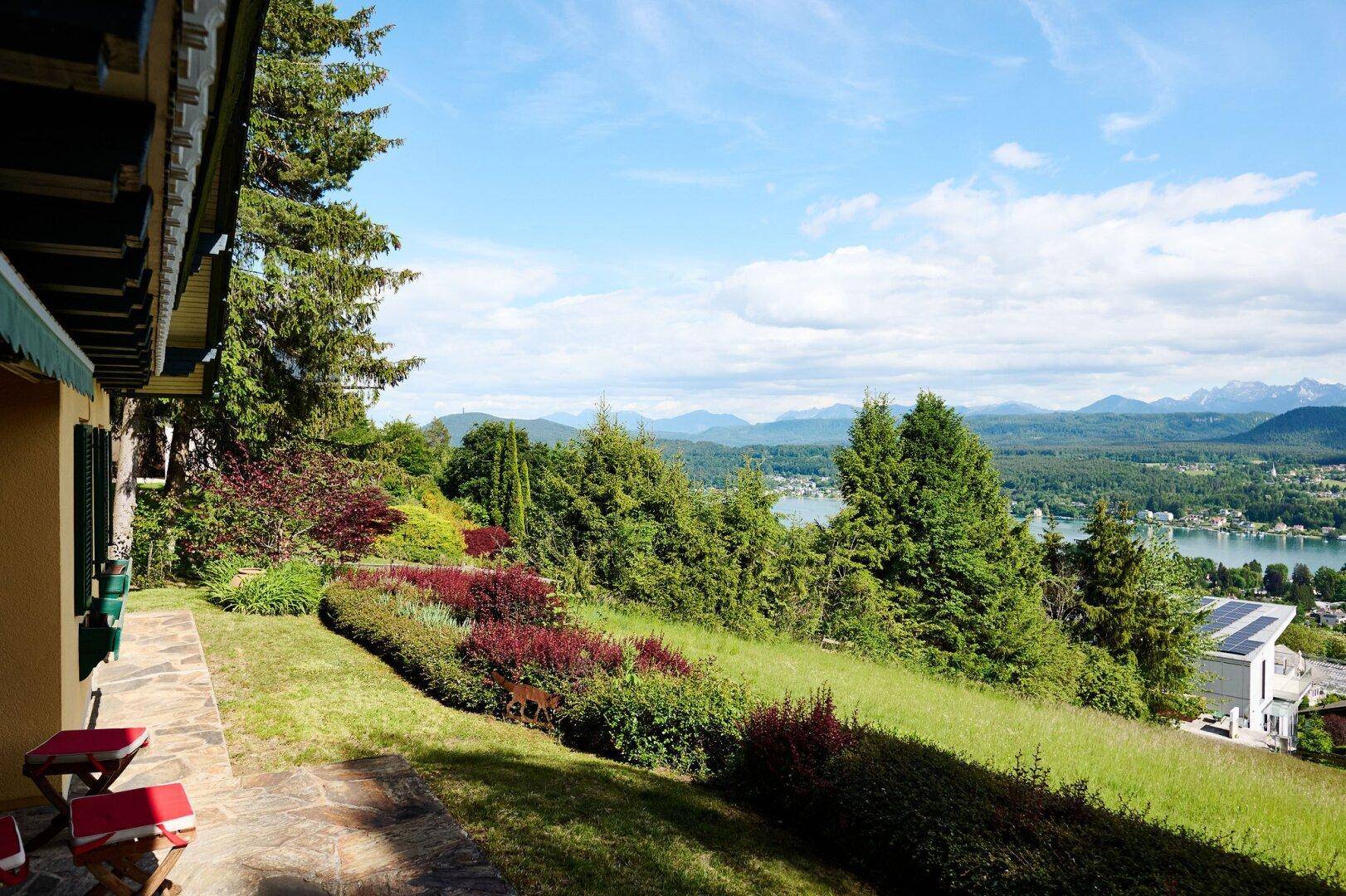 Steinterrasse mit farbenfrohen Blumenbeeten und einem atemberaubenden Panoramablick auf See und Berge.