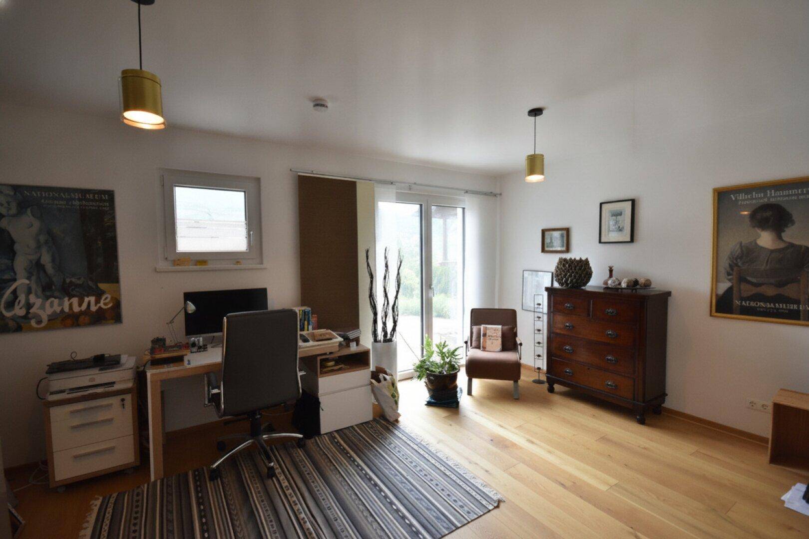 Helles Arbeitszimmer mit Holzboden, Schreibtisch und Zugang zur Terrasse.