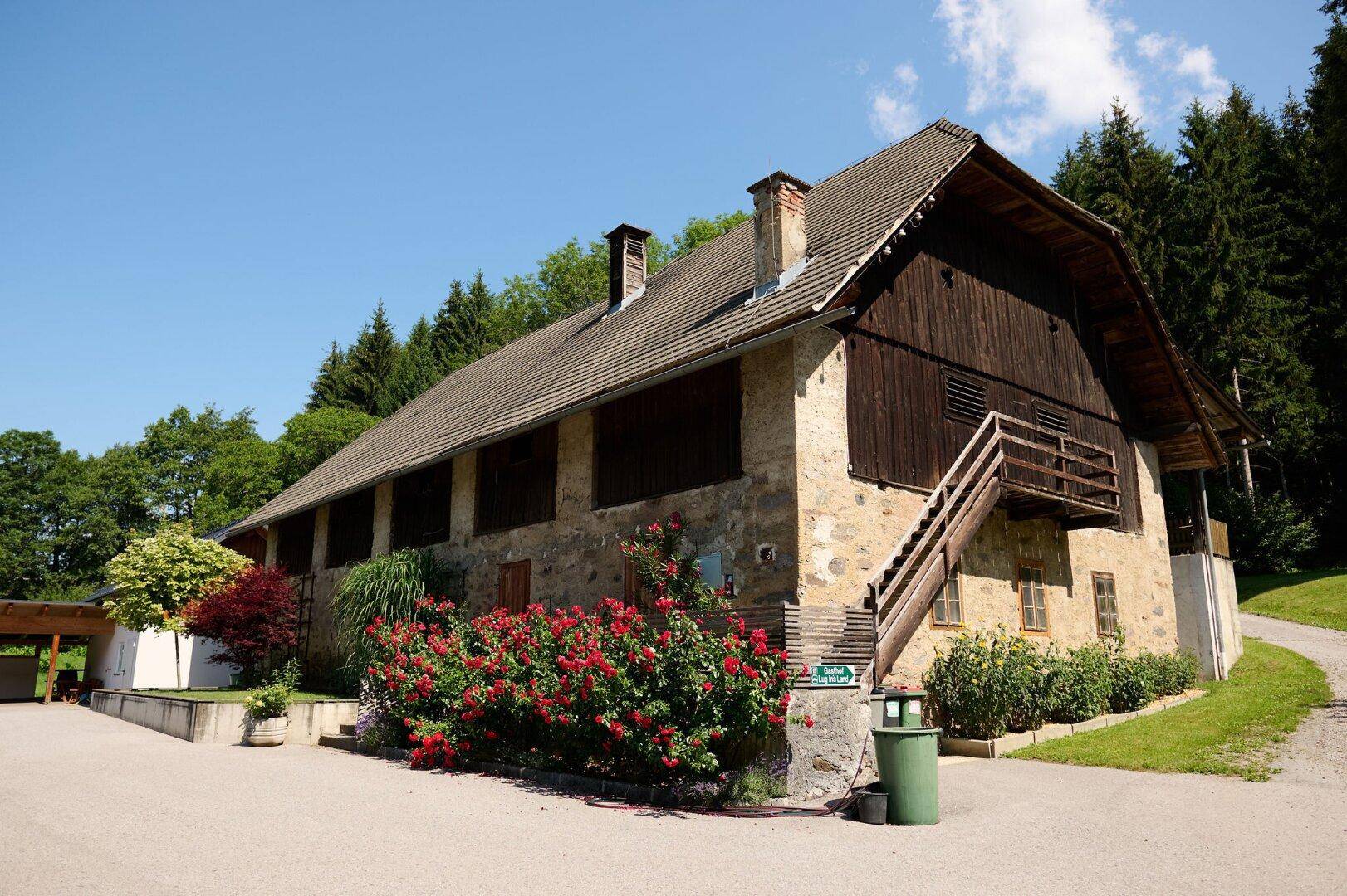 Traditionelles Gebäude aus Stein und Holz mit rustikalem Charme und blühenden roten Rosen im Vordergrund.
