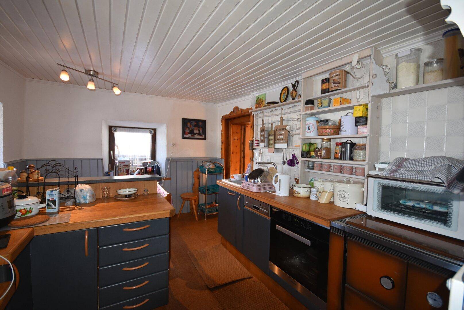 Traditionelle Küche mit dunklen Schränken, Holz-Arbeitsplatten und offenen Regalen.
