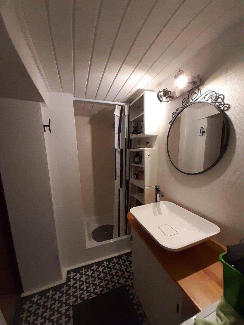 Modernes Badezimmer mit Duschkabine, stilvollem Waschbecken und runden Spiegel.