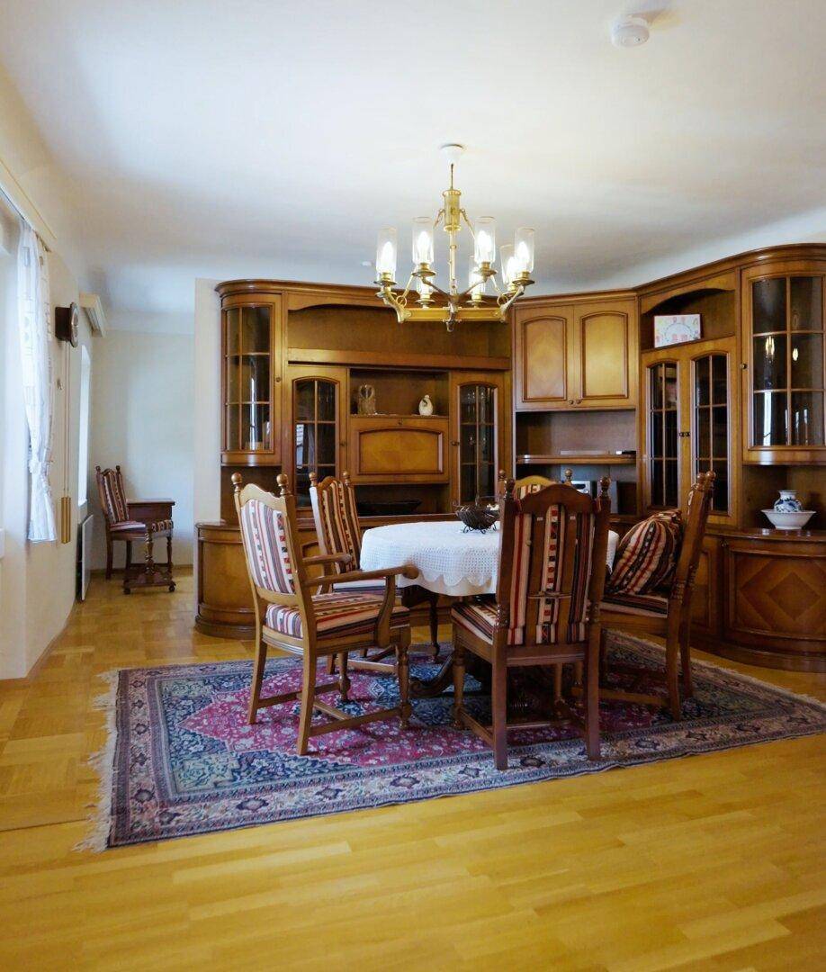 Eleganter Essbereich mit Holzboden, großem Esstisch und traditionellen Holzschränken.