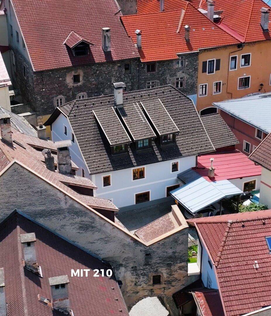 Luftaufnahme eines historischen Gebäudes mit Dachgauben, umgeben von weiteren Dächern der Altstadt.