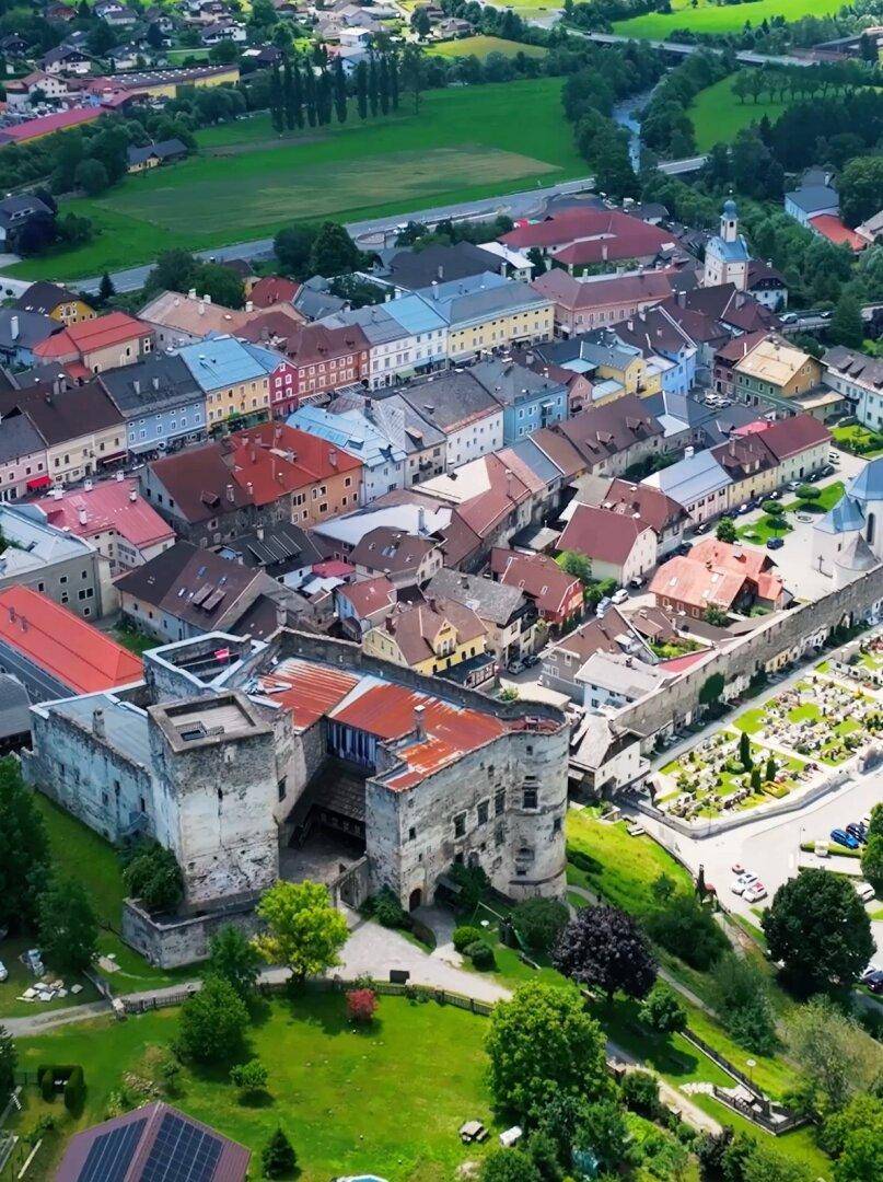 Malerische Luftaufnahme einer historischen Stadt mit Burg, Fluss und grüner Landschaft.