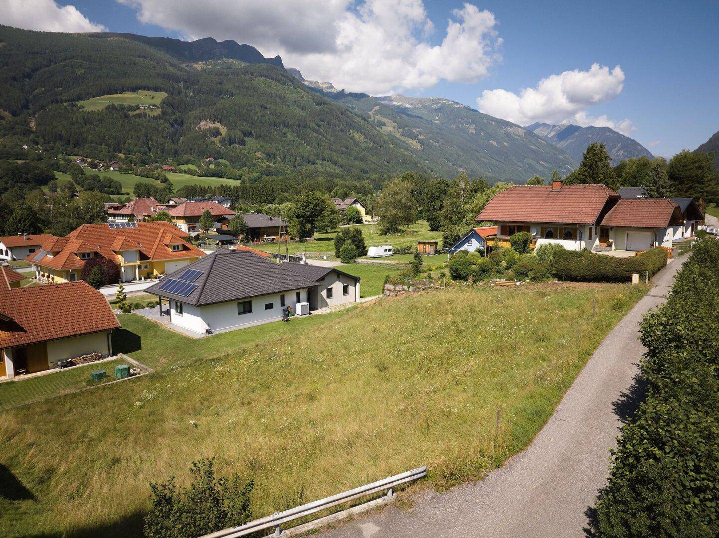 Weitläufige Ansicht eines Wohngebiets mit freiem Grundstück und beeindruckendem Bergpanorama.