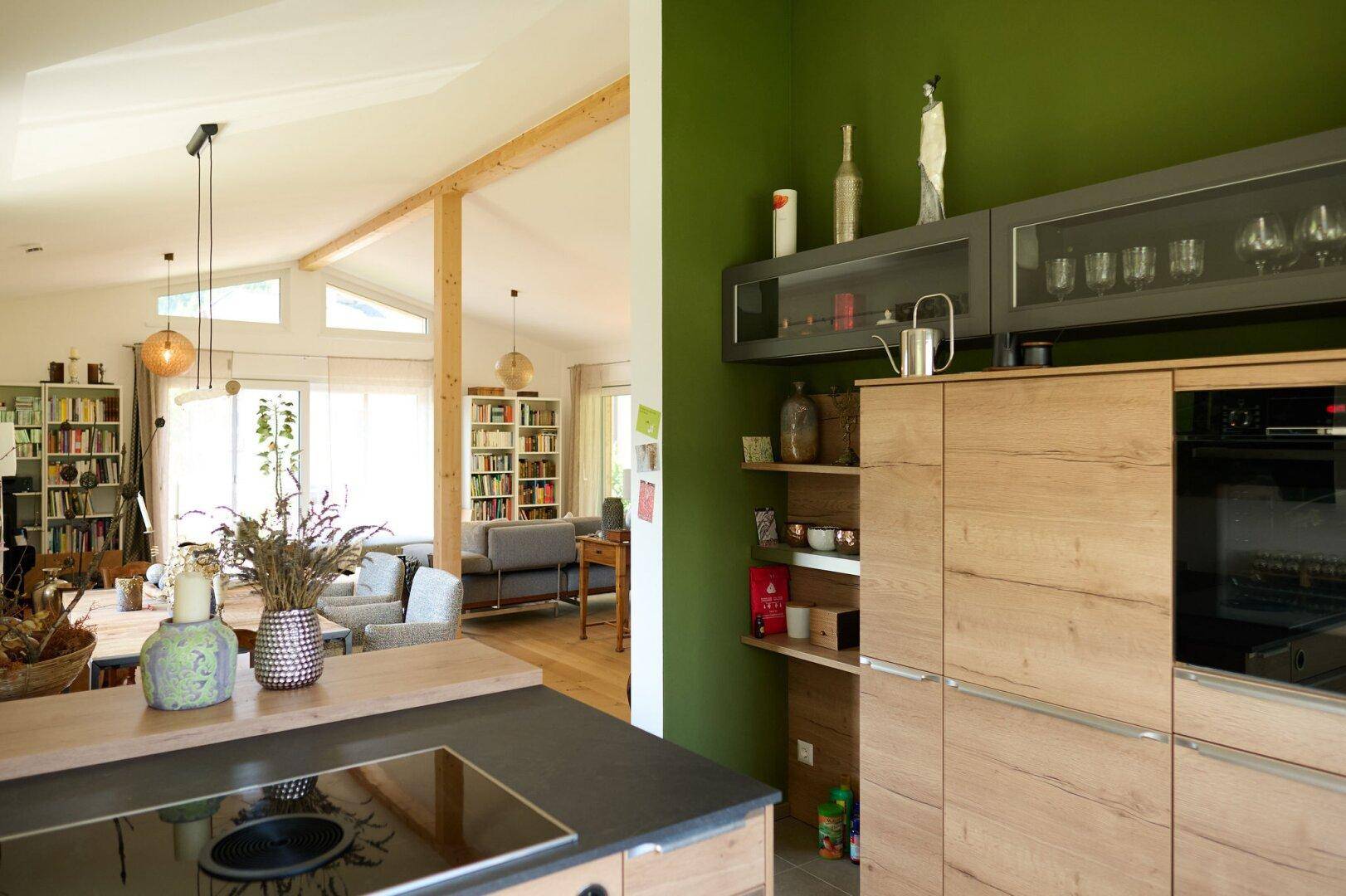 Moderne Küche mit grünen Wänden, Holzschränken und offener Verbindung zum Wohnbereich.