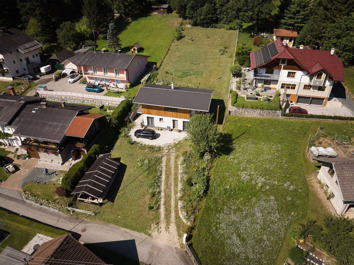 Luftaufnahme eines modernen Hauses mit großem Grundstück und umliegender Natur.