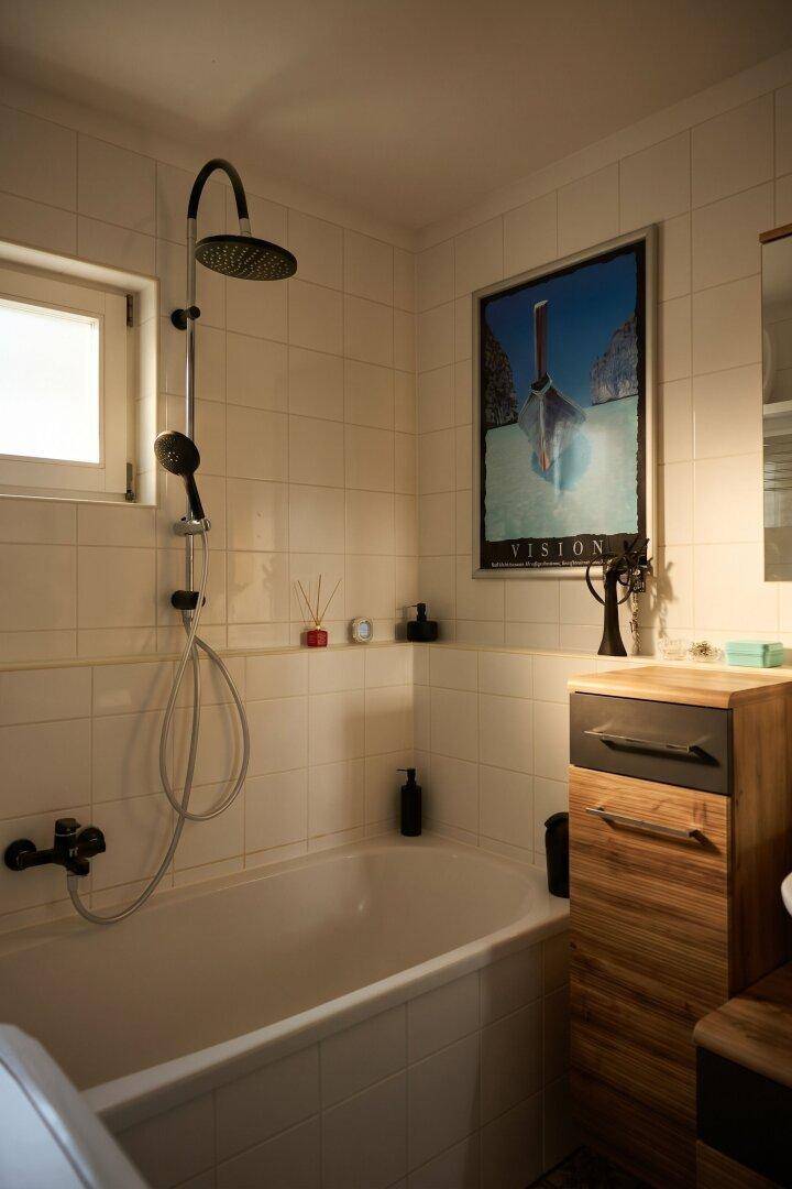 Badezimmer mit Badewanne, Duschfunktion und kleinem Fenster für Belüftung.
