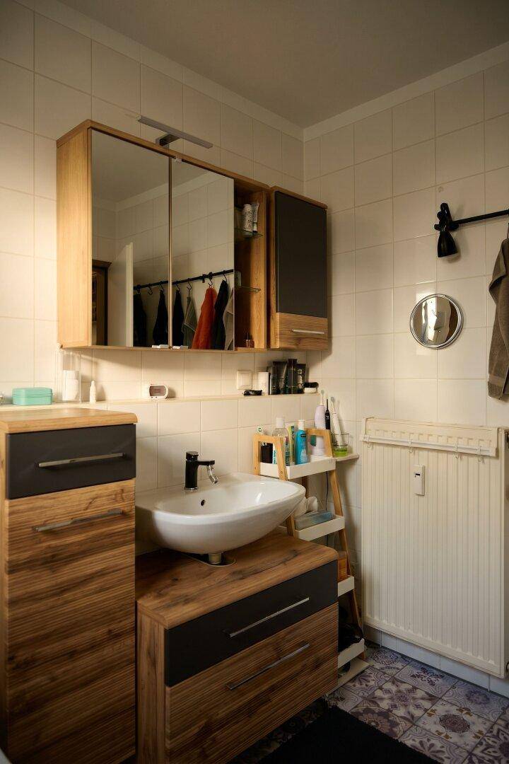 Badezimmer mit Einzelwaschbecken, Spiegelschrank und Heizkörper.