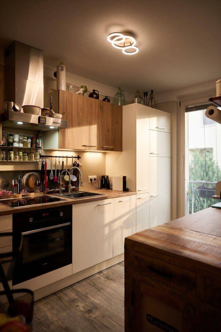 Moderne Einbauküche mit Holzdetails, Fenster und viel Arbeitsfläche.